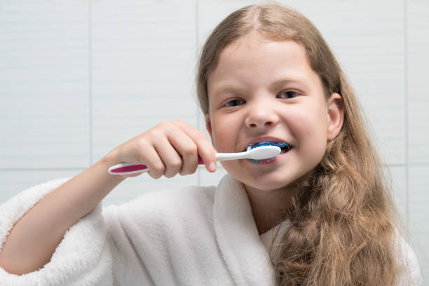 istock girl in white coat brushing her teeth, close-up 1163196190