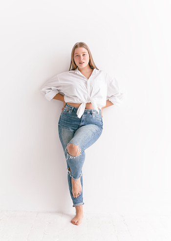 Young beautiful blond woman wearing stylish simple clothes white shirt blue jeans looking confident fresh and lovely Plus size Fashion model studio portrait on white background