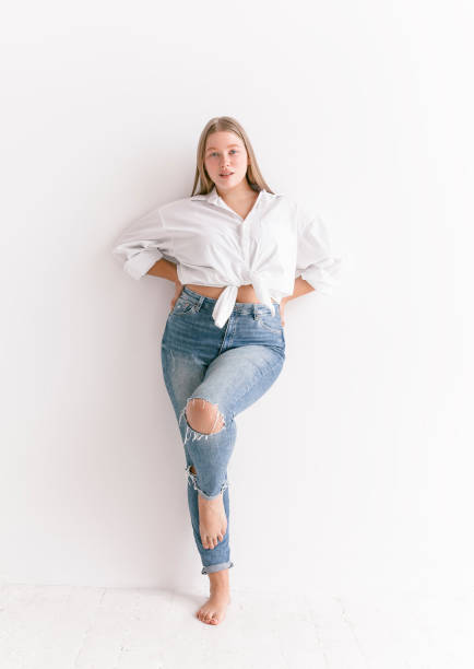 Gorgeous plus size fashion model in white shirt and blue jeans Natural beauty woman Young beautiful blond woman wearing stylish simple clothes white shirt blue jeans looking confident fresh and lovely Plus size Fashion model studio portrait on white background preppy fashion stock pictures, royalty-free photos & images