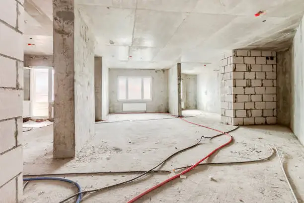 Photo of Construction site of residential apartment building interior in progress with windows and white brick wall