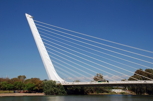 Seville, Spain - April 3, 2019: People cross the Puente del Alamillo (Alamillo Bridge) leading to Cartuja island. Designed by Santiago Calatrava, the bridge was completed in 1992 for the Universal Exposition.