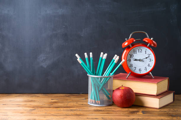 istock Back to school background with pencils, apple, books and alarm clock over chalkboard 1163201093