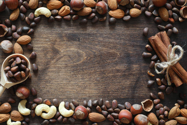 istock Different nuts on a wooden table. Cedar, cashew, hazelnut, walnuts and a spoon on the table. Many nuts are inshell and chistchenyh on a wooden background. 1163208384