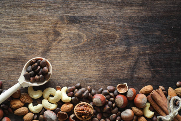 istock Different nuts on a wooden table. Cedar, cashew, hazelnut, walnuts and a spoon on the table. Many nuts are inshell and chistchenyh on a wooden background. 1163208420
