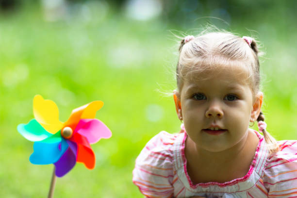 istock Child with Pinwheel in the summer park looking at camera 1163210825
