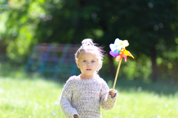 istock Child with Pinwheel in the summer park looking at camera 1163211208