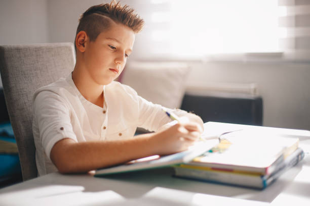 istock Teenager sitting at the table doing his school homework. 1163214496