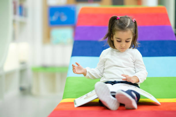 a menina bonito está lendo o livro na biblioteca do berçário - picture book library preschool bookshelf - fotografias e filmes do acervo