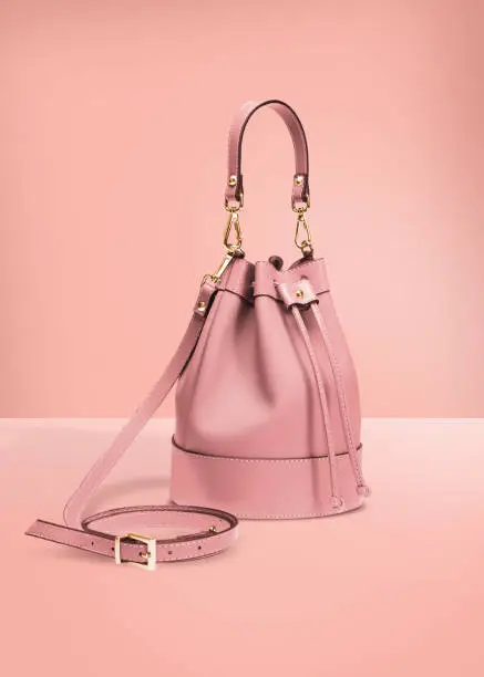 Fashion photography, pink color designer bucket bag on a pastel pink background with clipping path