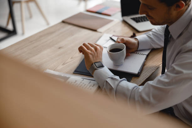 istock Man with coffee checking time on smart watch 1163222228
