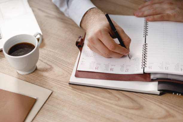 istock Man writing in daily planner with black pen 1163222236