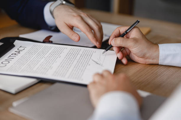istock Hand pointing to the contract while another person signing it 1163222279