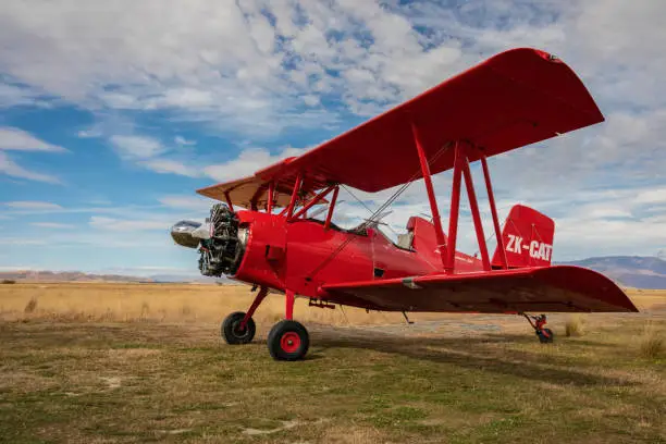 A Bright red Grumman Ag-Cat Biplane on a field