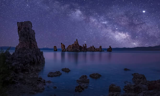 Mono Lake Starry Night The Milky Way galaxy core shines in the sky above on a dark moonless night sky over the Tufa columns of Mono Lake with a large tufa in the foreground and an island of tufas as dark silhouettes seen on the horizon. Mono Lake stock pictures, royalty-free photos & images