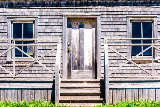 Old vintage abandoned wooden house with door porch entrance in idyllic rural countryside in summer