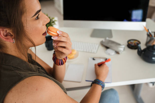 istock Woman having a snack while working at office desk 1163242260