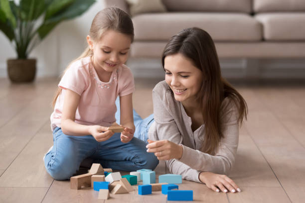 istock Smiling mom and little daughter playing with toy blocks 1163242816