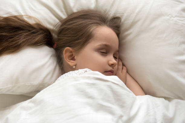 istock Peaceful little girl sleeping in cozy white bed 1163242826