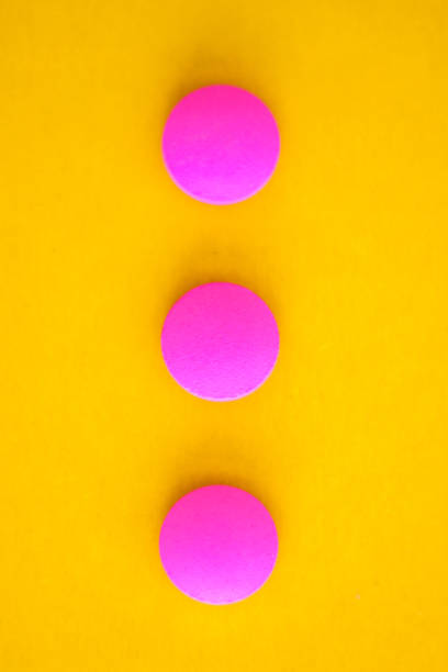 istock Composition of three pink round pills on a yellow background. Flat lay. Copy space. Trend Close-up 1163243062