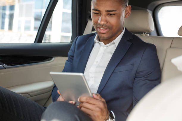 istock Young businessman sitting on back seat in car watching video happy 1163243452