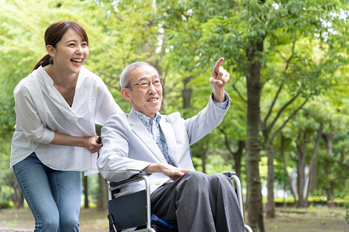 young asian woman and old asian man with wheelchair in park