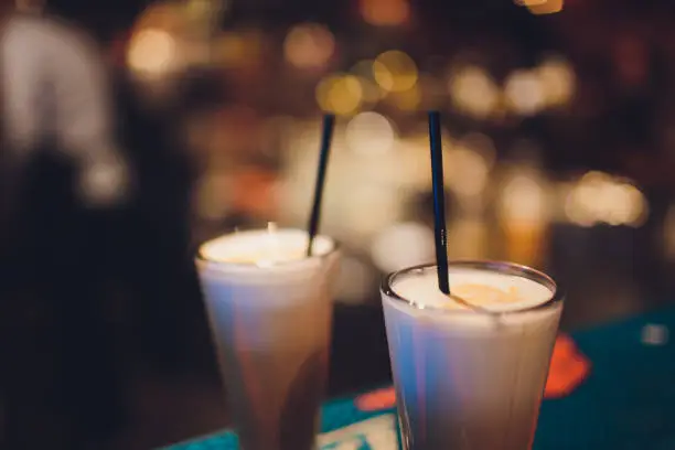 Two delicious thick icecream milkshakes garnished with chocolate and mint and served in tall chilled glasses on a small old wooden tray