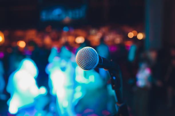 istock microphone on a stand up comedy stage with colorful bokeh, high contrast image. 1163244355