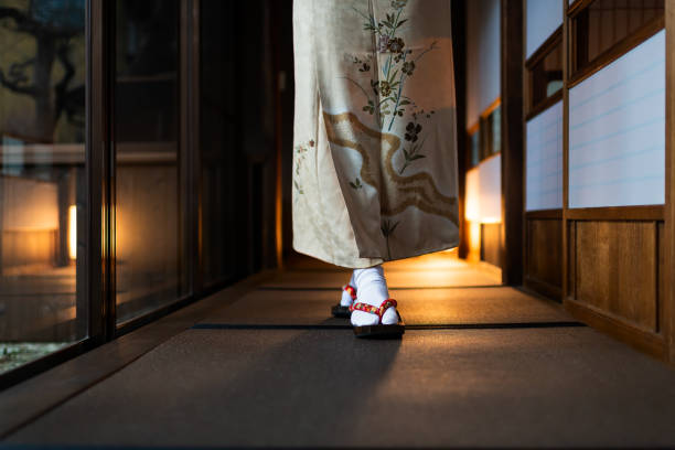 Traditional japanese house or ryokan with tatami mat floor and shoji sliding paper doors and woman in kimono and geta shoes tabi socks walking Traditional japanese house or ryokan with tatami mat floor and shoji sliding paper doors and woman in kimono and geta shoes tabi socks walking geta sandal photos stock pictures, royalty-free photos & images
