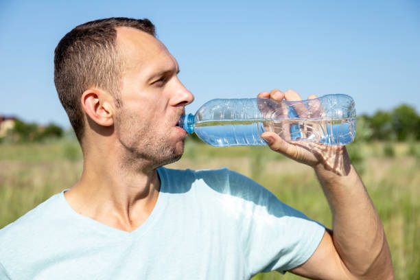 istock young man drinking water from a bottle in nature 1163249538