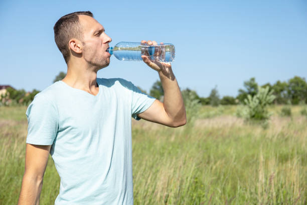 istock young man drinking water from a bottle in nature 1163249592