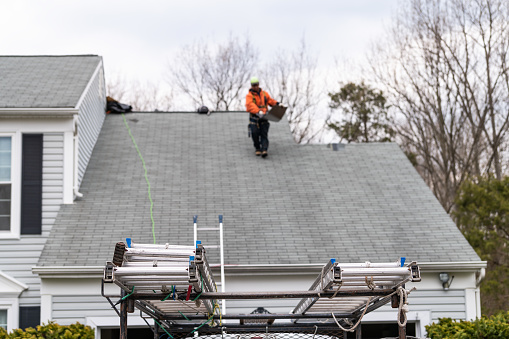 Casa durante el día sobre el garaje con camión, color gris Casa unifamiliar y hombre caminando sobre tejas del techo y escalera durante la reparación photo