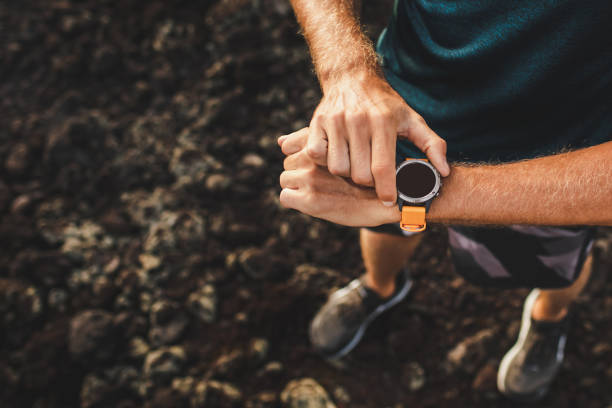 istock Young athletic man using fitness tracker or smart watch before run training outdoors. Close-up photo with dark background. 1163253867