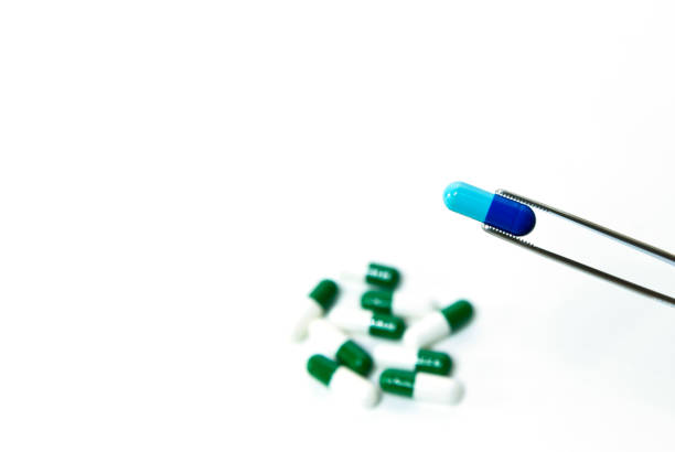 A researcher pick up and select the novel capsule drug to treat orphan diseases with forceps stock photo