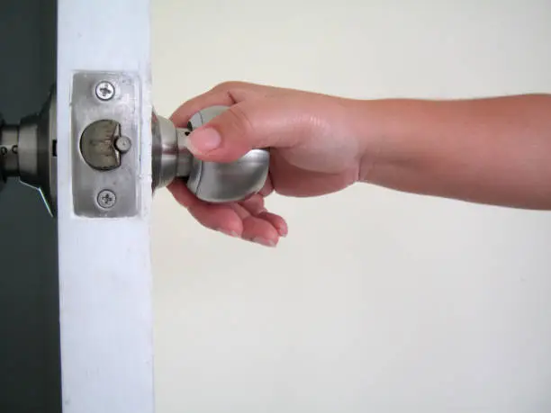 The hand is twisting the knob to open the door. Open the whitedoor with the keys. Door knob with a key.