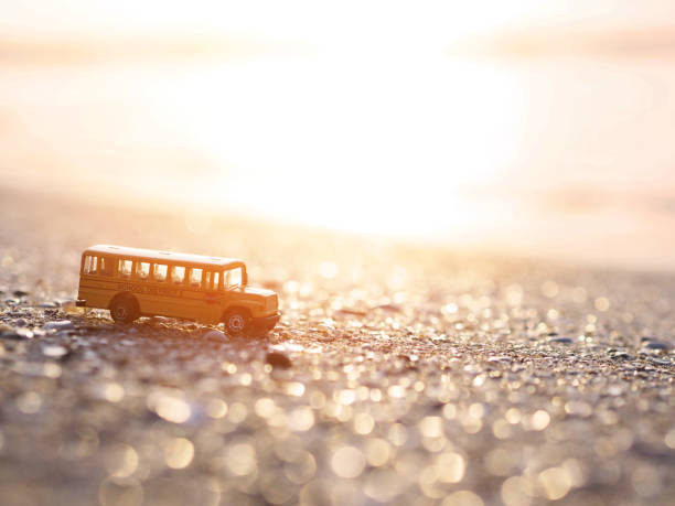 giocattolo scuolabus sulla sabbia sullo sfondo della spiaggia al tramonto. - school bus defocused education bus foto e immagini stock
