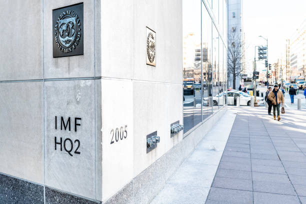 IMF entrance with sign of International Monetary Fund, logo, headquarters 2, two, HQ2 with people walking on sidewalk, street stock photo