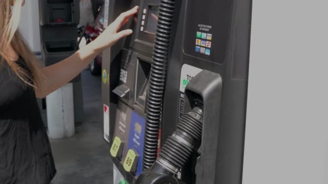 woman pays for gas and uses pump