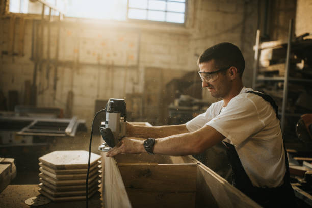 istock Young carpenter working with plane on a piece of wood in workshop. 1163286190