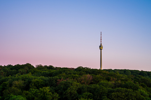 Germany, Illuminated famous television tower of stuttgart city inside endless green forest of trees in magical dawning twilight atmosphere after sunset