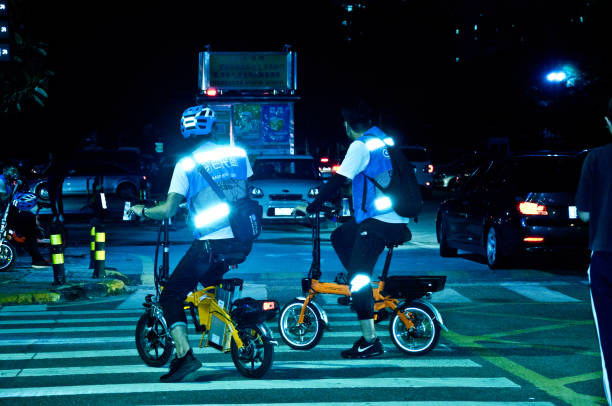 Vehicular and human traffic (incl. tourists and city workers on e-bikes) at night in Futian Central Business District, Shenzhen - China. stock photo