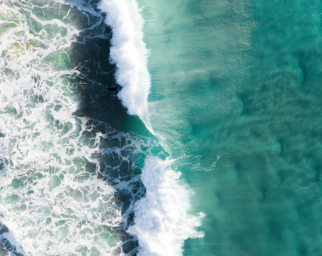Wave crashing in the blue turquoise ocean. Aerial of a rolling strong and powerful wave in the sea at sunrise