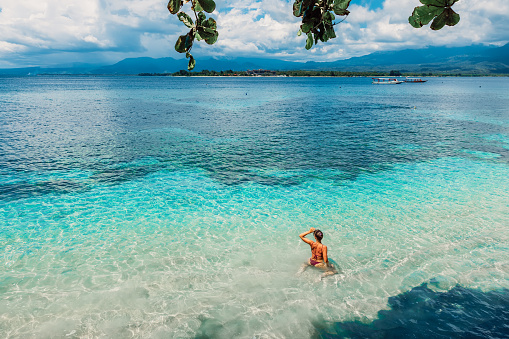 Young bikini woman relax in blue ocean on tropical island