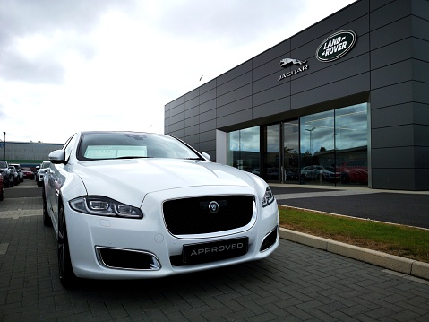 Cardiff, UK: July 20, 2019: Used Jaguar XJ car for sale outside a Jaguar Land Rover showroom. Jaguar Land Rover Limited is a British multinational automotive company.