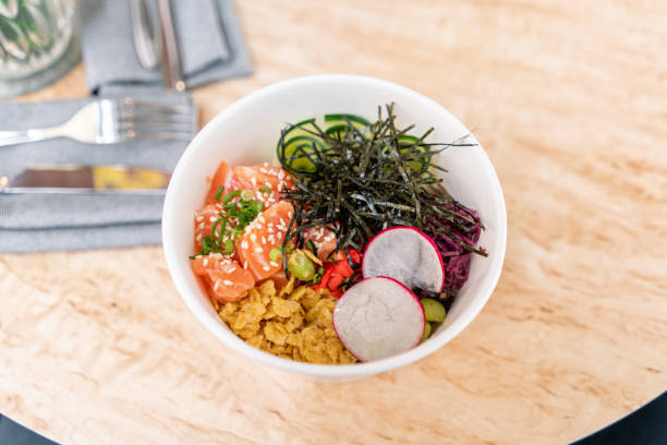 traditional hawaiian dish poke bowl with fork. hawaiian salmon fish with rice, radish,cucumber, tomato, sesame seeds and seaweeds. diet and useful fast food - poking prepared ahi tuna hawaiian culture imagens e fotografias de stock