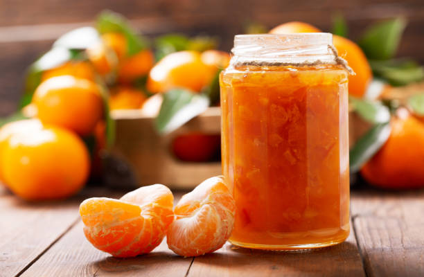 glass jar of orange tangerine or mandarin jam with fresh fruits stock photo