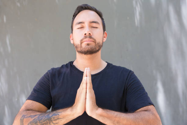 istock Young man with closed eyes praying 1163307911
