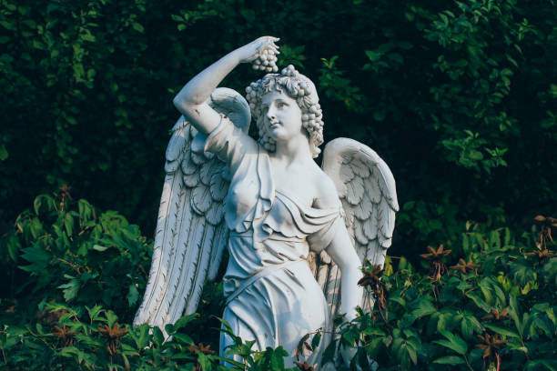 hojas verdes y escultura de ángel con alas - roman statue angel rome fotografías e imágenes de stock