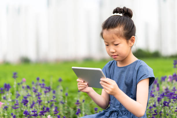 istock Asian little girl using digital tablet on the lawn 1163311579