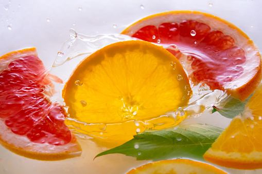 Citrus slices get into clean and clear water, create waves and splashes