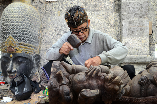 BALI, INDONESIA- 14 FEB, 2019: Man is making wooden crafts in Bali island, Indonesia